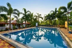 Pool framed by tall palms — PN Nature's Paradise Villa, Igatpuri