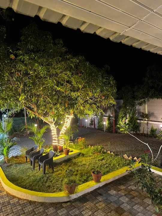 Garden seating under string-lit mango trees at PN Nature's Paradise Villa, Igatpuri