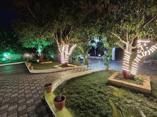 Lawns and lit trees after sunset — PN Nature's Paradise Villa, Igatpuri